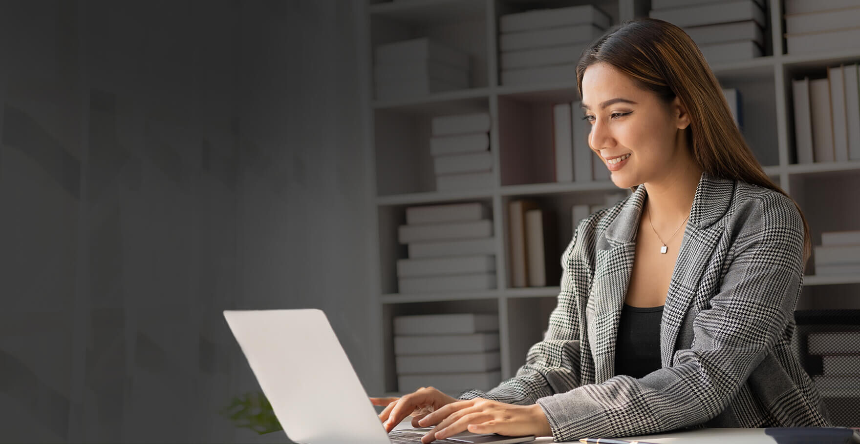 Woman in business attire working at a laptop
